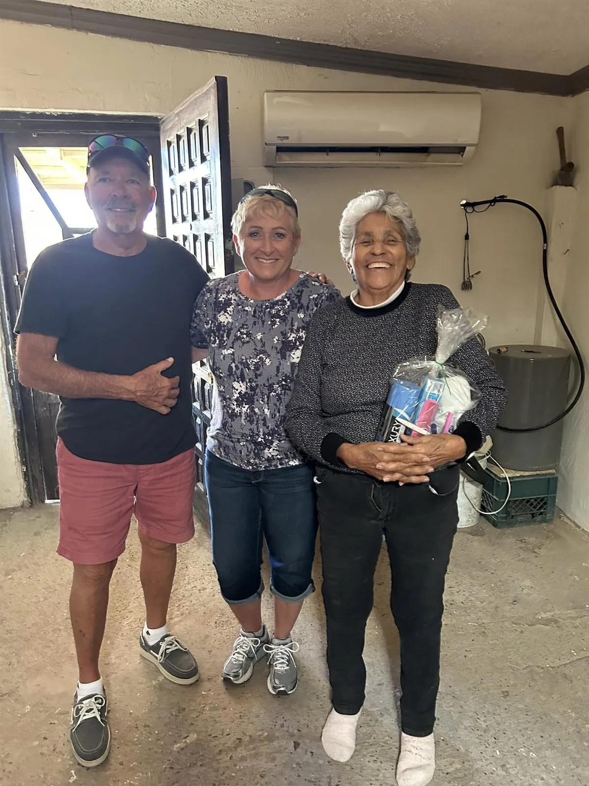 Volunteers with a woman receiving a care package of essentials from Faith Family Church Rocky Point