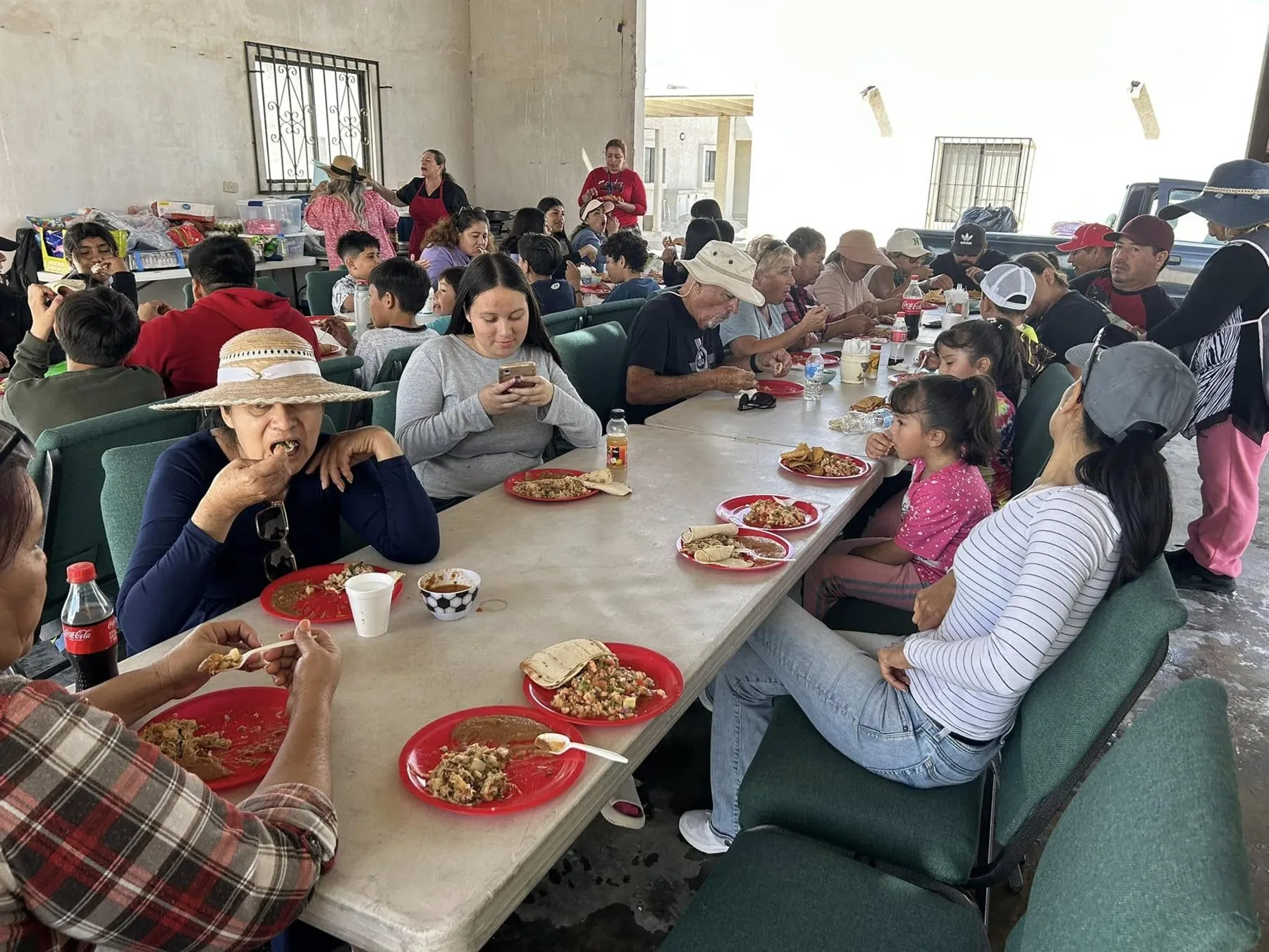 Neighbours of all ages eating together at long tables under a shade structure at Faith Family Church Rocky Point