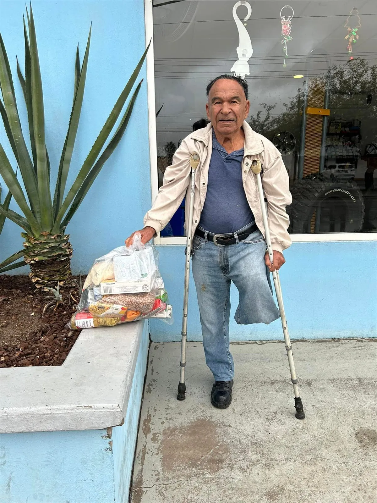 A man on crutches carrying a bag of donated groceries from Faith Family Church Rocky Point