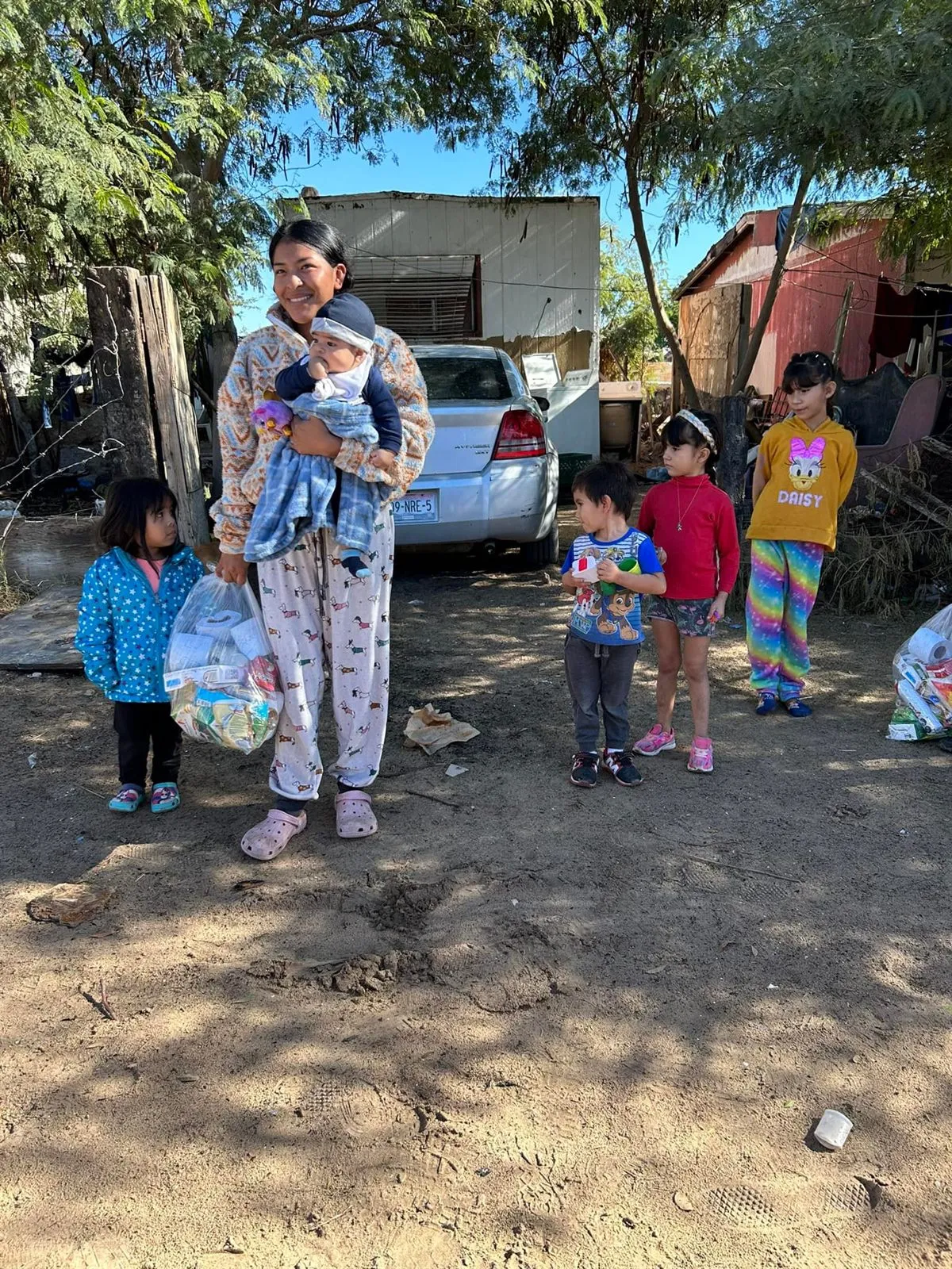 A mother and her children receiving a bag of groceries from Faith Family Church Rocky Point