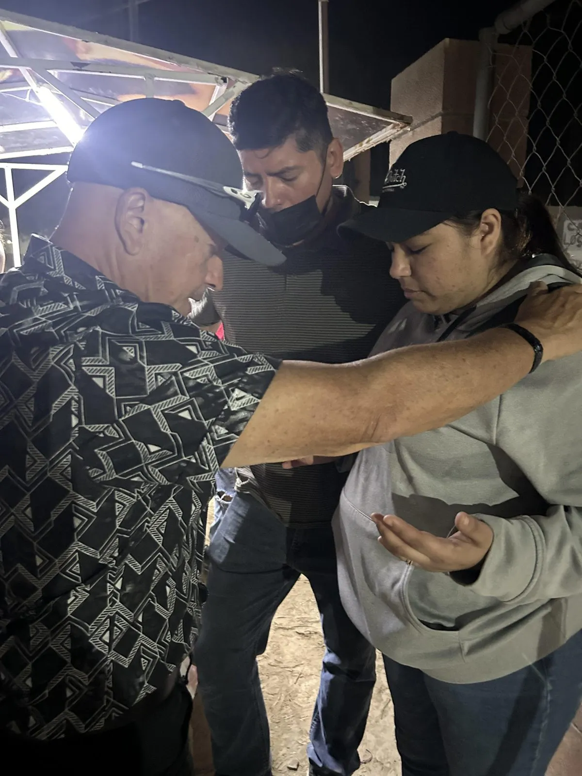 Members of Faith Family Church Rocky Point praying with a neighbour on the street at night in Puerto Penasco