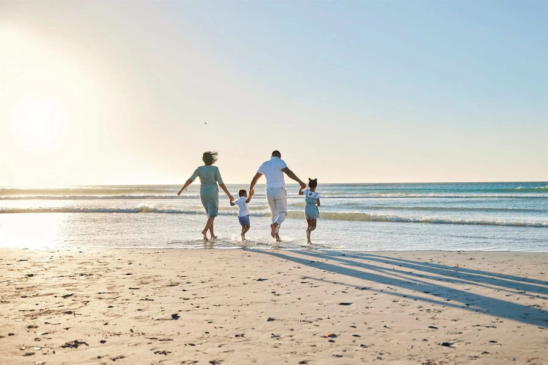 A family walking into the surf at sunset on the beach in Rocky Point, Puerto Penasco, Mexico