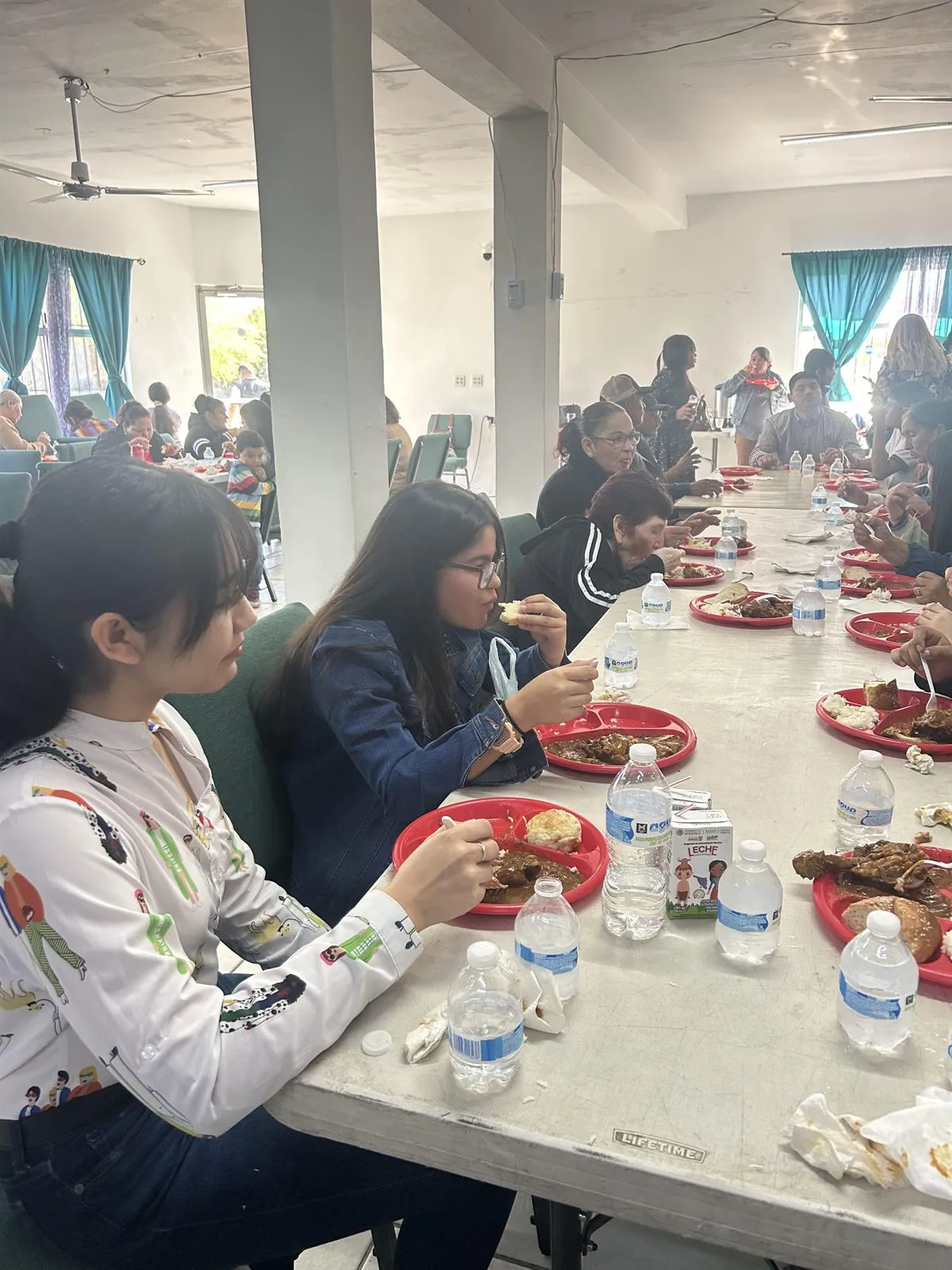 Young people sharing a hot meal at a long table inside Faith Family Church Rocky Point