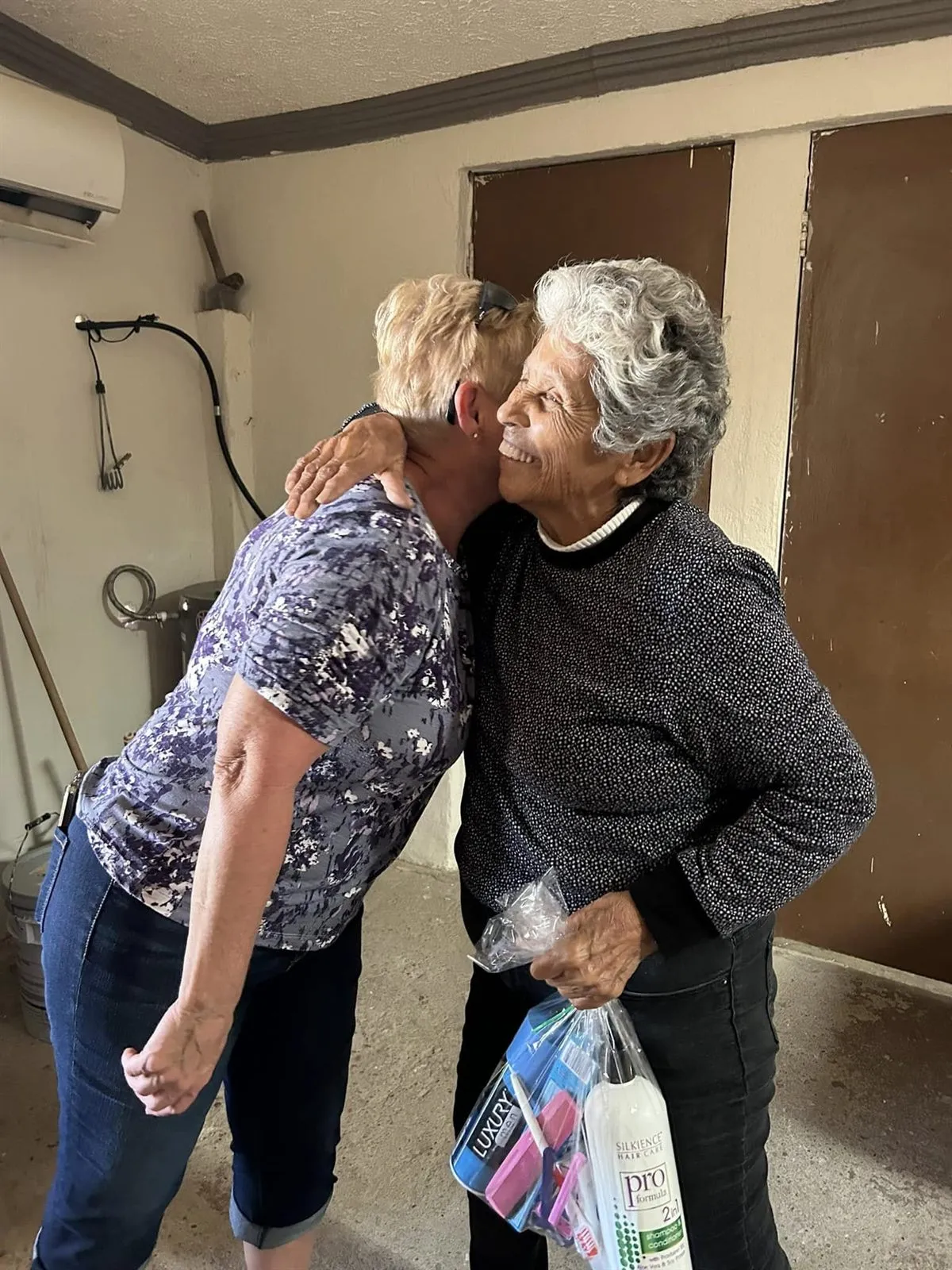 A visiting volunteer embracing a local woman after a giveaway at Faith Family Church Rocky Point