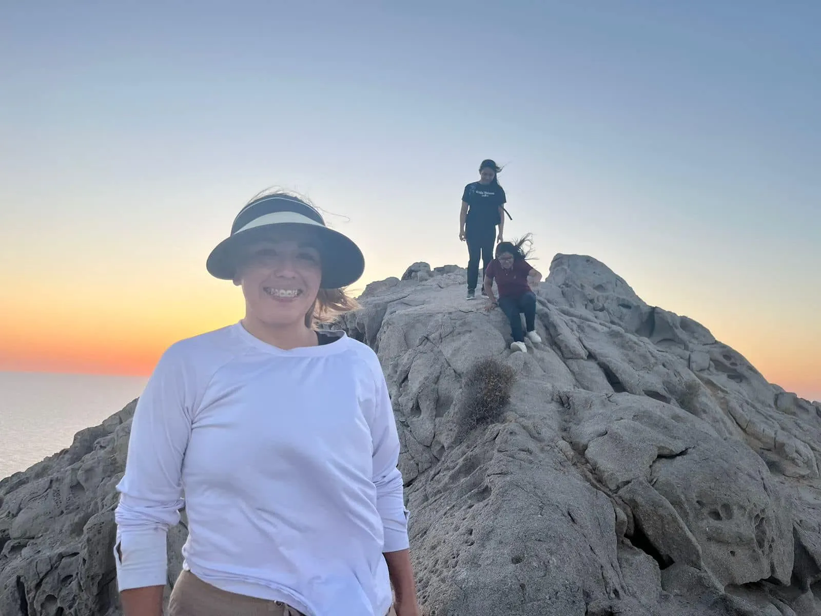 Young people from Faith Family Church Rocky Point on the rocks above the ocean at sunset during youth camp